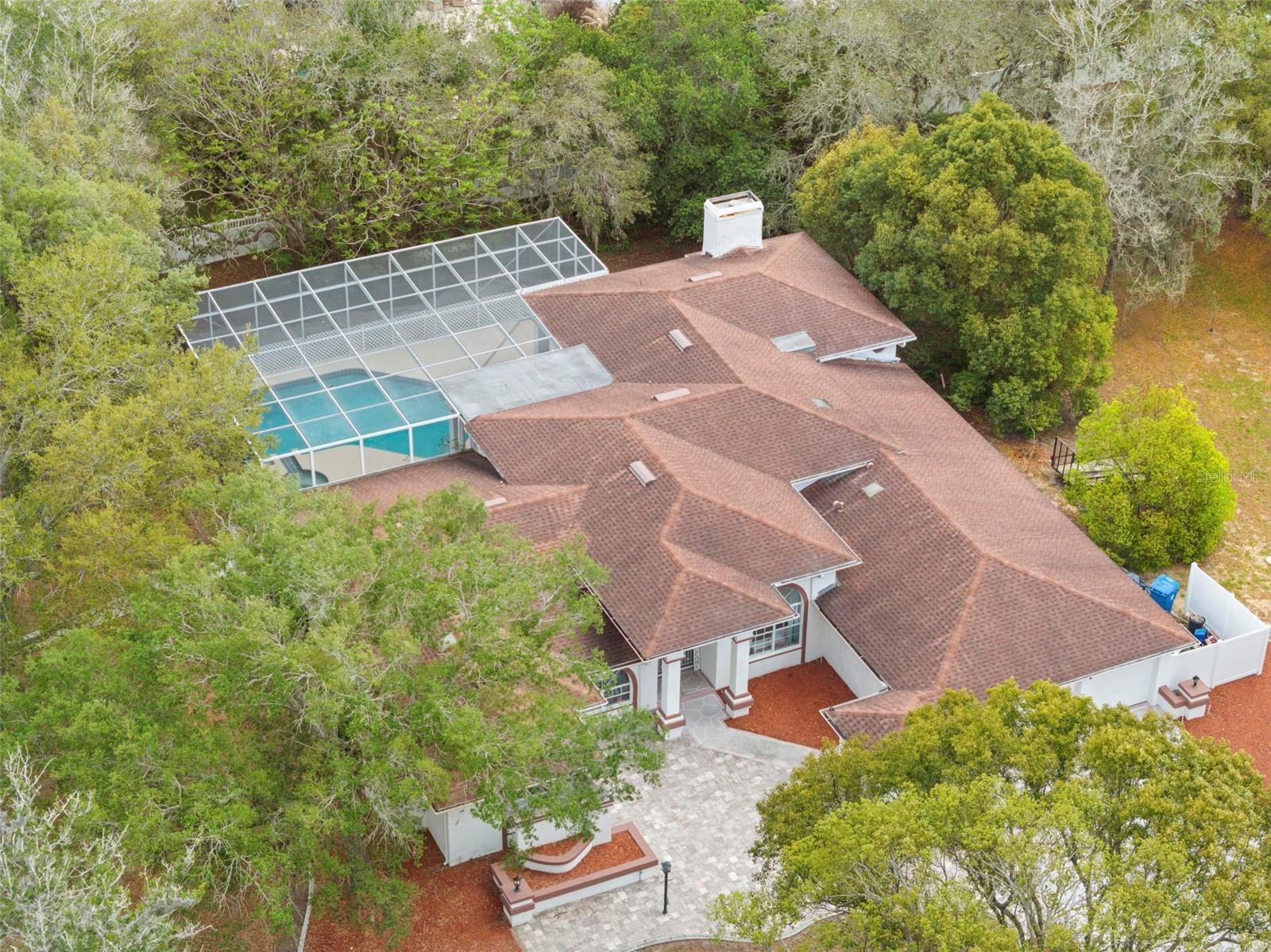 Aerial view of a tile-roof pool home with screened enclosure in East Linden Estates, Spring Hill FL